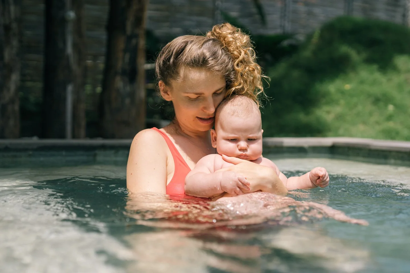 Une mère tient son bébé contre elle dans une piscine