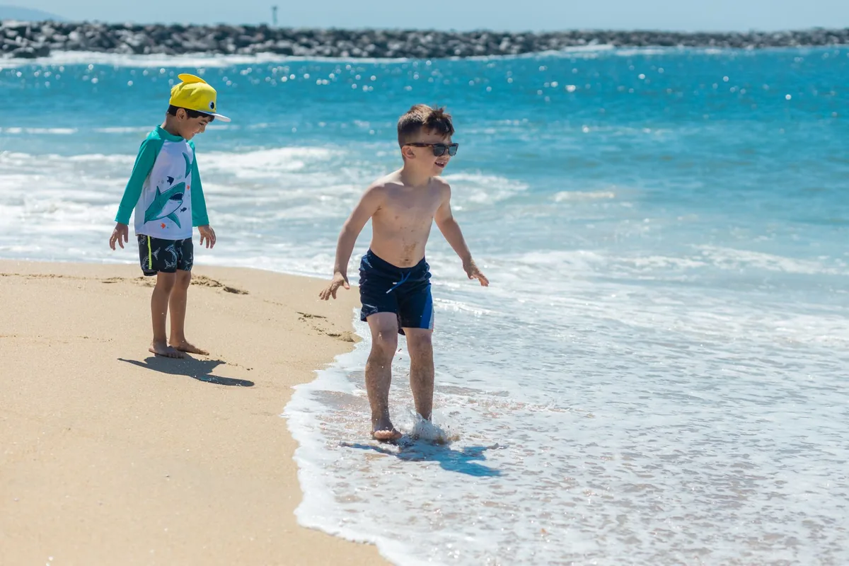 Two young boys enjoy a sunny day at the beach, playing near the ocean waves