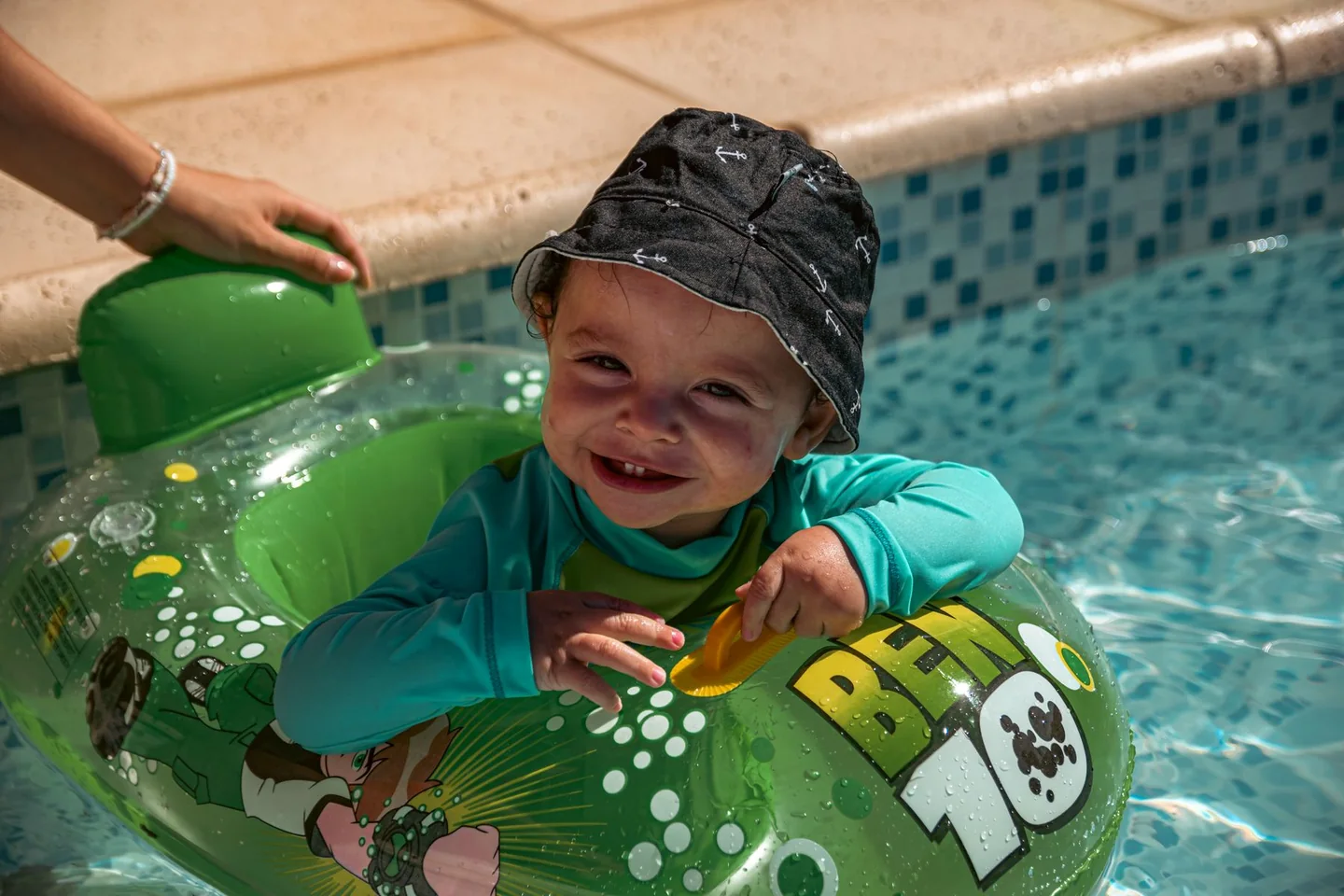 Jeune enfant protégé par un chapeau et un haut couvrant dans une piscine